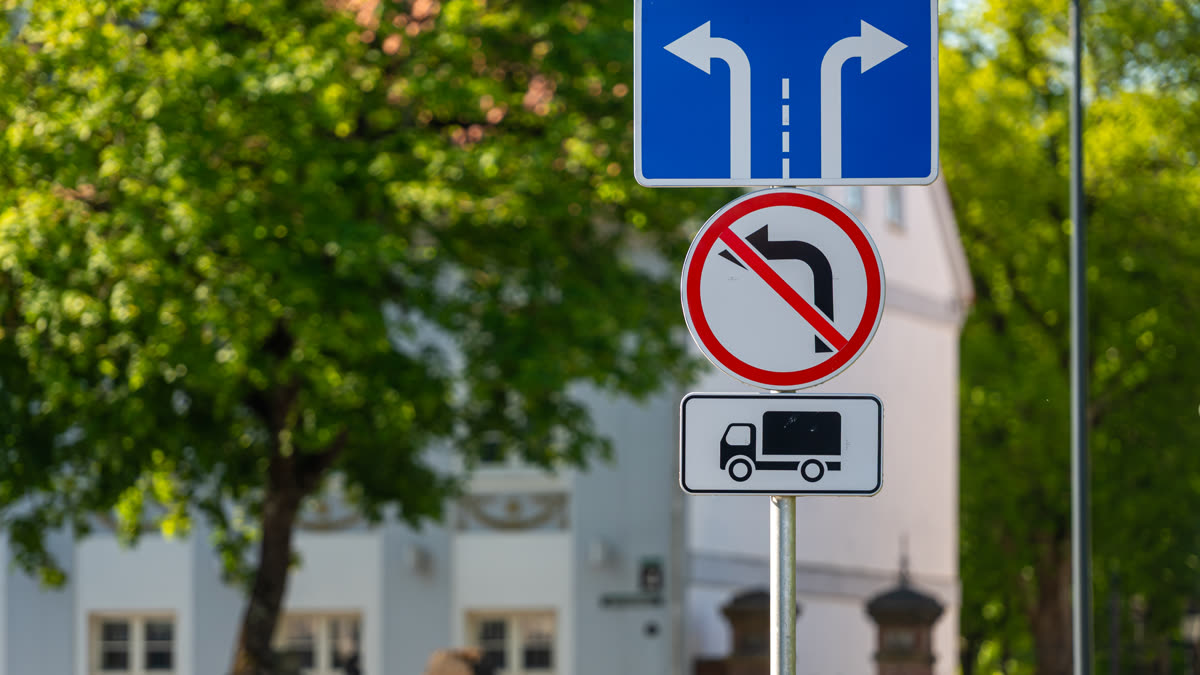 Dopravné značky na stĺpe v obytnej zóne — informačná, zákazová a dodatková tabuľka.