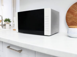 Ilustračný stock: mikrovlnka a domáci router v kuchyni, bez loga a bez čitateľnej obrazovky.